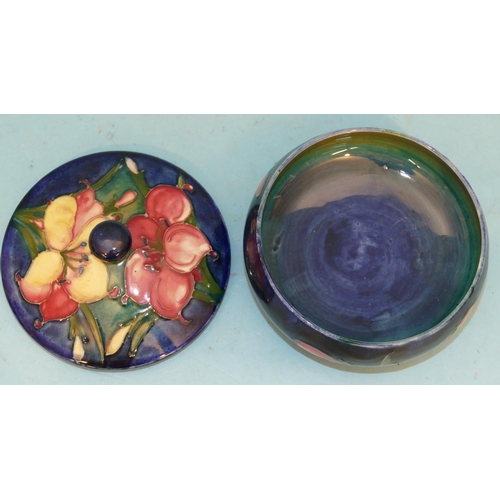 113 - A Moorcroft Small Round Bulbous Lidded Dressing Table Pot on blue ground with multicoloured floral a... 