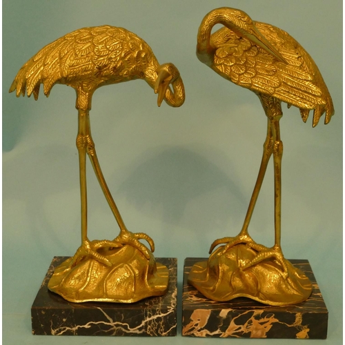 604 - A Pair of Brass Figures of Cranes, on black marble bases, 34cm high.