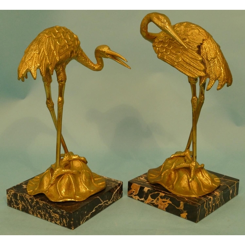 604 - A Pair of Brass Figures of Cranes, on black marble bases, 34cm high.