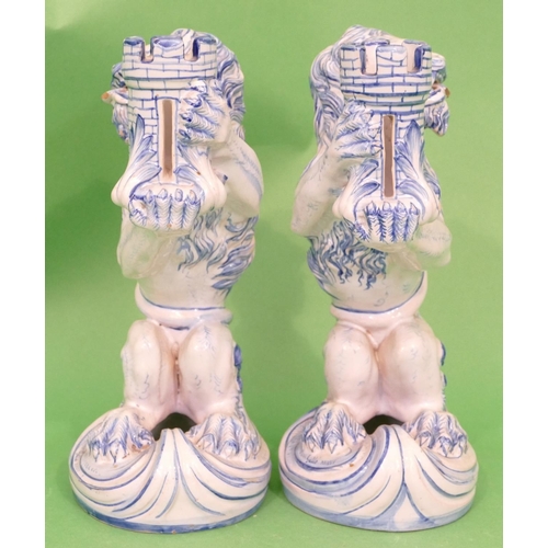 129 - A Pair of Continental Glazed Majolica Candlestick in form of seated lions holding turrets on blue an... 