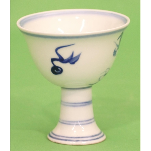 22 - An Oriental Blue and White Round Cup having dragon decoration on sweeping foot, 9cm high.