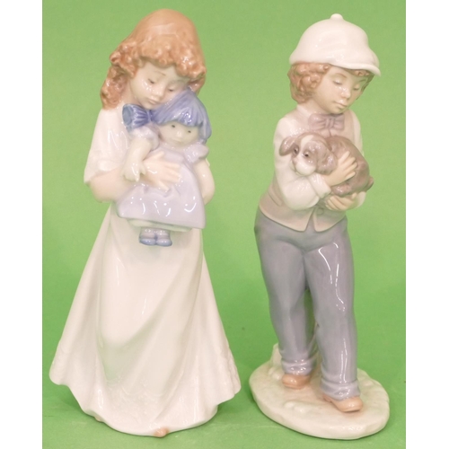 26 - 2 x Nao Figures of young girl holding rag doll and boy holding puppy, 20.5cm high.