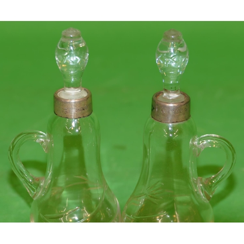 367 - A Pair of Plain Glass Round Bulbous Small Jugs with stoppers having London silver necks, 12cm high.