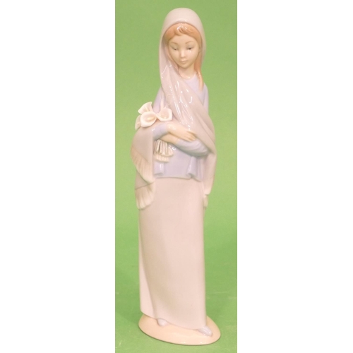 43 - A Lladro Figure of a young standing lady holding lilies, 23.5cm high.