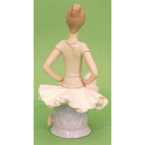 45 - A Lladro Figure of a young ballerina seated upon a pouffe, 23.5cm high.