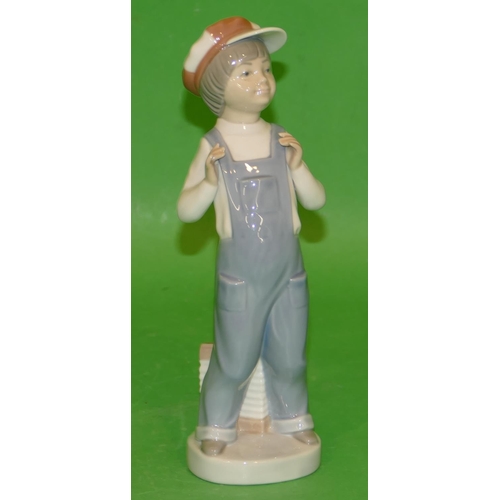 156 - A Lladro Figure of a young boy wearing dungarees and cap, 22cm high.