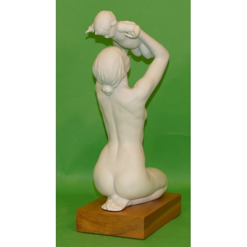 190 - A Lladro Matt White Figure of a female kneeling nude, holding aloft her child on rectangular hardwoo... 