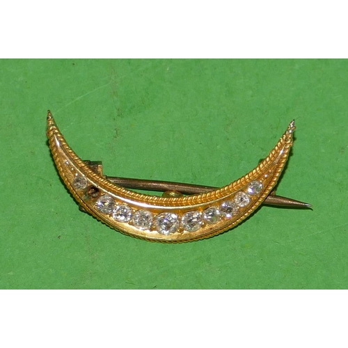 543 - A Small Gold Crescent Moon Brooch mounted with graduated diamonds (1 diamond missing) 2.4cm wide.