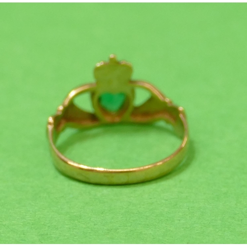 572 - A 9ct Gold Claddagh Ring in form of 2 hands holding a heart with crown motif, mounted with green sto... 