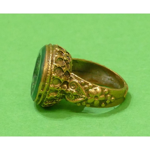 676 - A Roman Style Circular Ring with green stone, having figurehead decoration, size Q/R.