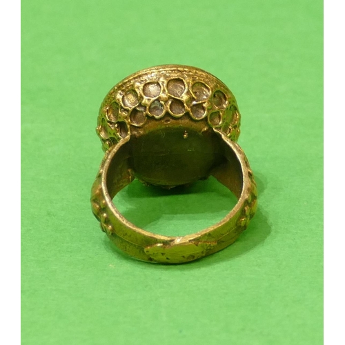 676 - A Roman Style Circular Ring with green stone, having figurehead decoration, size Q/R.