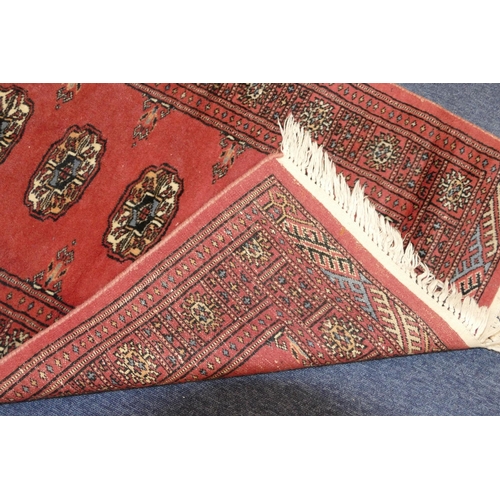 702 - A Modern Eastern Rug on red ground having 5 centre medallions, 1m 18cm x 77cm.