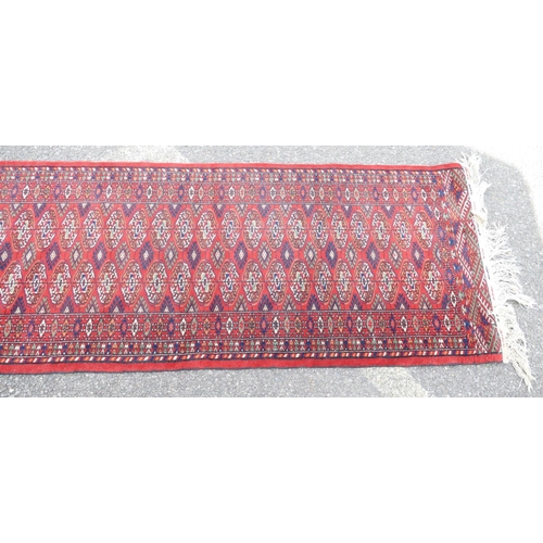 711 - A Bokhara Wool Runner on red ground having blue and green centre medallion, 4m 4cm x 71cm.