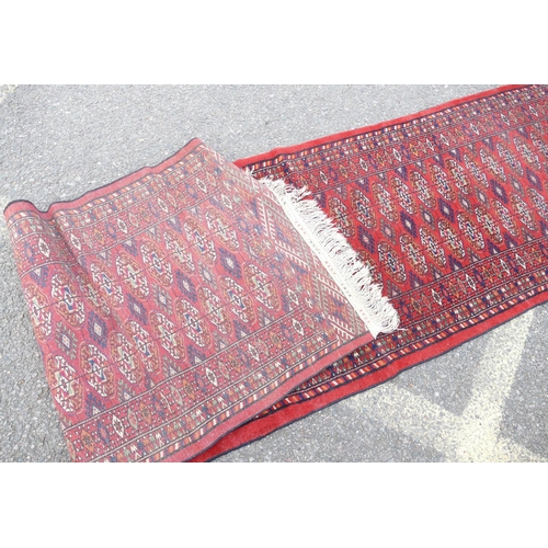 711 - A Bokhara Wool Runner on red ground having blue and green centre medallion, 4m 4cm x 71cm.