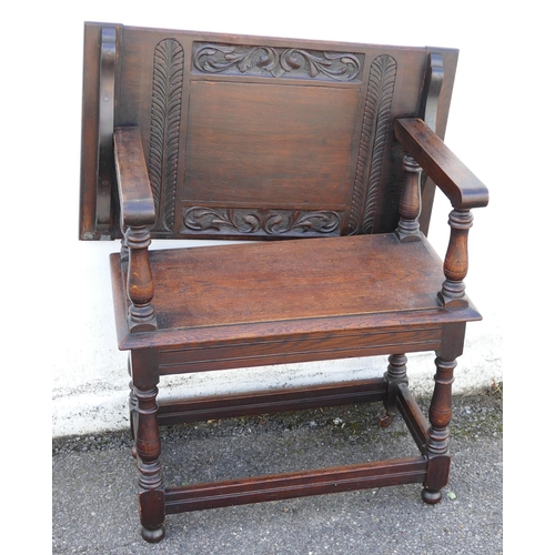 893 - An Oak Monks Bench having sliding top with carved leaf and scroll decoration, turned supports, solid... 