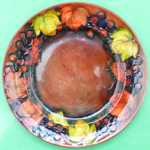 91 - An Early Moorcroft Side Plate on red ground with multicoloured pomegranate and leaf decoration, 16.5... 