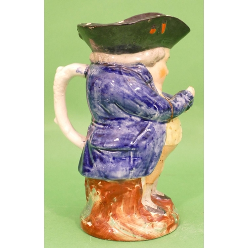 101 - A 19th Century Toby Jug in form of a standing potbellied gentleman in blue coat, taking snuff, 21.5c... 