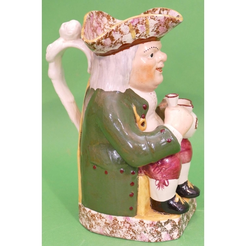 102 - A 19th Century Toby Jug in form of a seated gentleman in green coat holding jug and glass, having sp... 