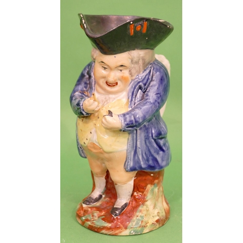 101 - A 19th Century Toby Jug in form of a standing potbellied gentleman in blue coat, taking snuff, 21.5c... 