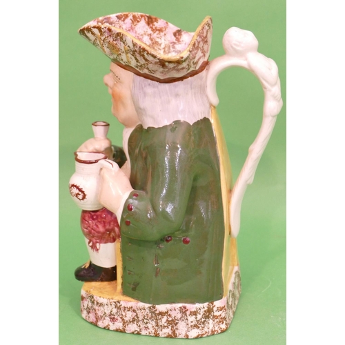 102 - A 19th Century Toby Jug in form of a seated gentleman in green coat holding jug and glass, having sp... 