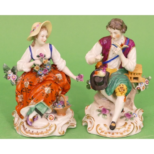 20 - A Pair of Continental Porcelain Figures of young seated gentleman and lady holding bird and encruste... 