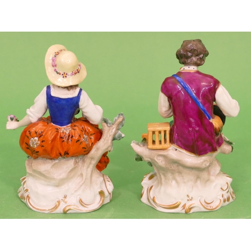 20 - A Pair of Continental Porcelain Figures of young seated gentleman and lady holding bird and encruste... 