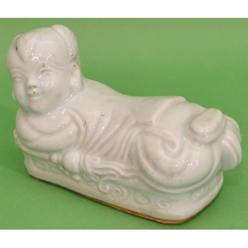 83 - An Oriental Glazed Earthenware Pillow in form of a child on pale green ground, 21cm long.