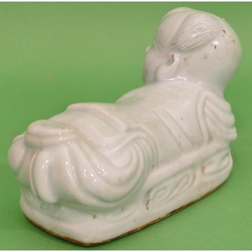 83 - An Oriental Glazed Earthenware Pillow in form of a child on pale green ground, 21cm long.