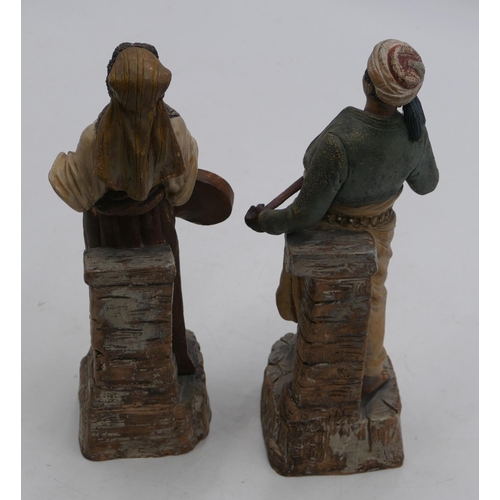 101 - A pair of Continental earthenware figures of standing gentleman and lady holding a sword and musical... 