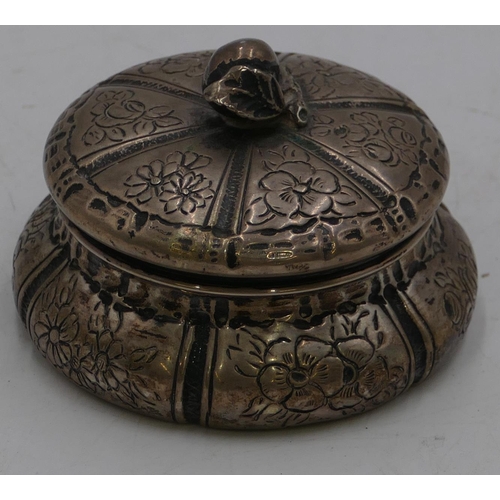 253 - An 800 silver coloured round bulbous shaped lidded pot with embossed floral and leaf decoration, 8cm... 