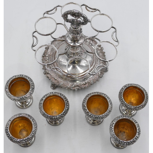 320 - A silver plated circular stand with centre carrying handle, mounted with 6 egg cups on 3 splayed fee... 