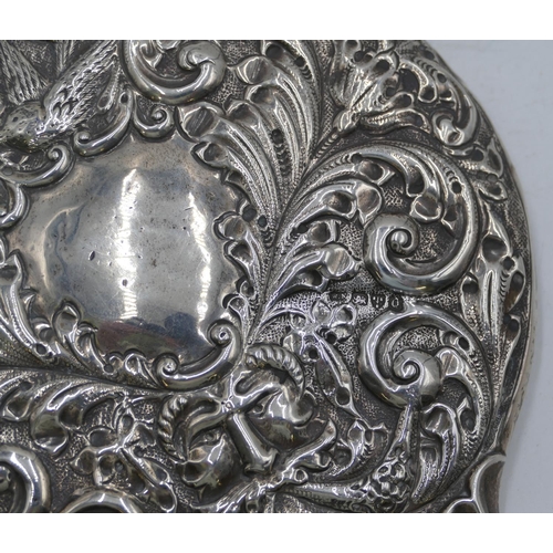 340 - A Chester silver hand mirror with allover embossed bird mask head, floral and scroll decoration, Che... 