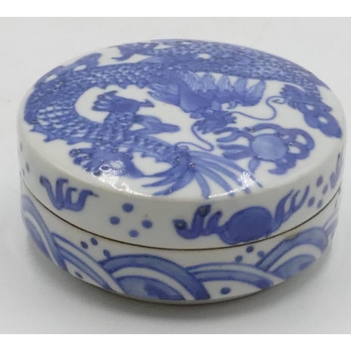 38 - An Oriental cylindrical lidded blue and white pot with dragon decoration, 10cm diameter, 4.5cm high.