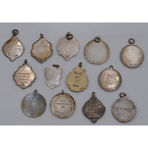 409 - 13 silver archery medals, some with enamelled decoration, 172.4 grams gross.