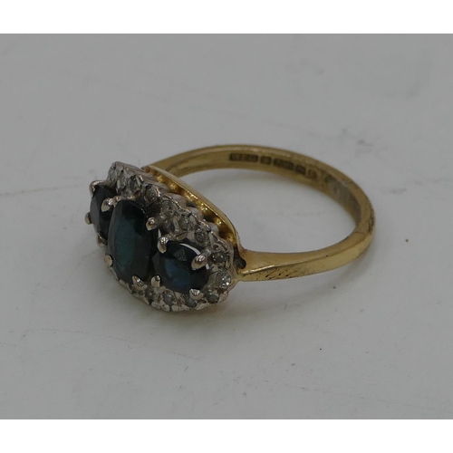 440 - An 18ct gold ladies cluster ring set with 3 sapphires and surrounded by small diamond chips, size L,... 