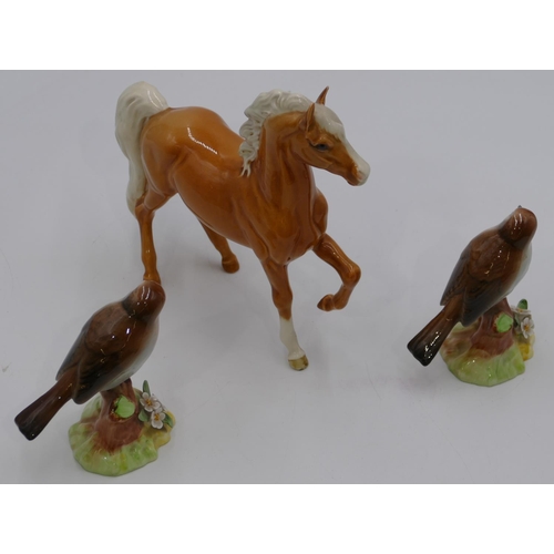 45 - A Beswick figure of a horse, 17cm high, 2 Raybur figures of perched robins. (3)