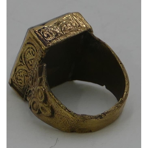 473 - A brass rectangular shaped ring set with pale green stone with engraved decoration, size T.