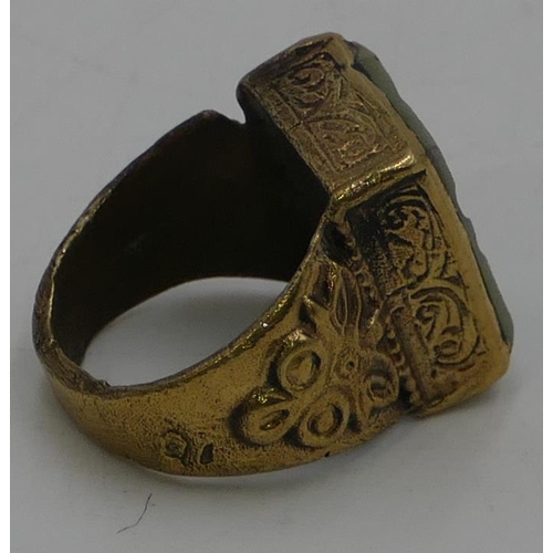 473 - A brass rectangular shaped ring set with pale green stone with engraved decoration, size T.