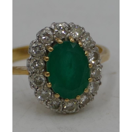 489 - An 18ct gold ladies oval cluster ring set with centre emerald, surrounded by diamonds, size N/O