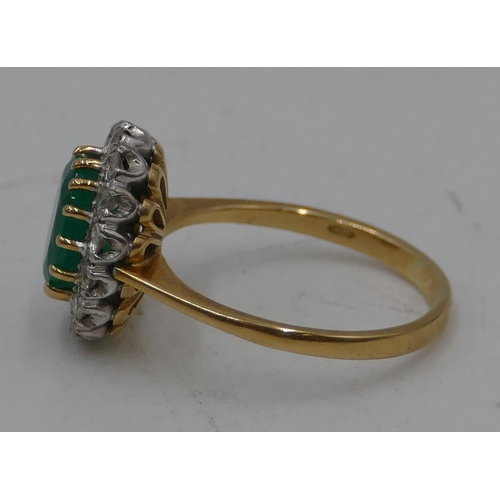 489 - An 18ct gold ladies oval cluster ring set with centre emerald, surrounded by diamonds, size N/O