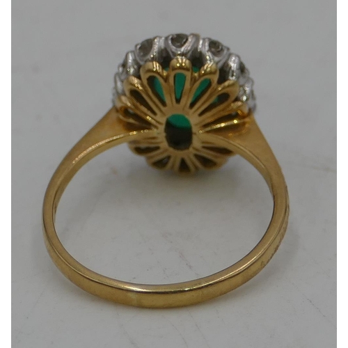 489 - An 18ct gold ladies oval cluster ring set with centre emerald, surrounded by diamonds, size N/O