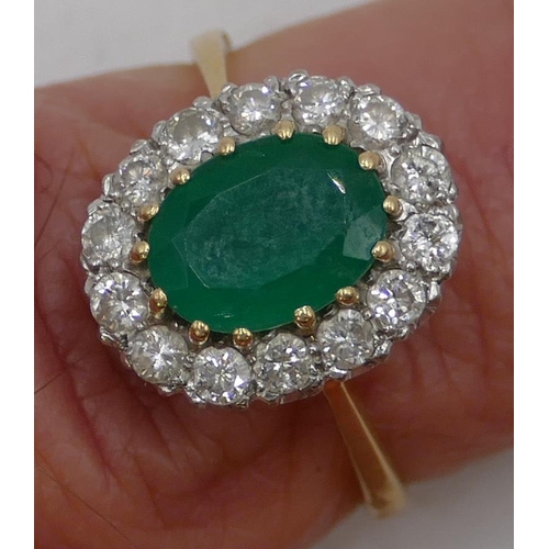 489 - An 18ct gold ladies oval cluster ring set with centre emerald, surrounded by diamonds, size N/O