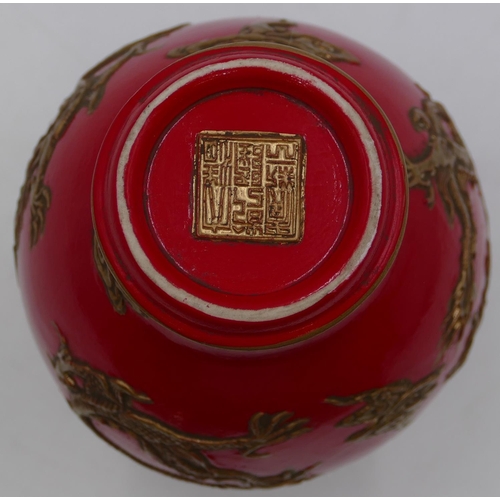 56 - An Oriental round bulbous thin necked trumpet shaped vase on red ground with raised gilt dragon deco... 