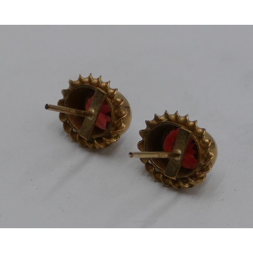 560 - A pair of 14ct oval gold earrings set with garnets, 1.8g gross (no butterflies),