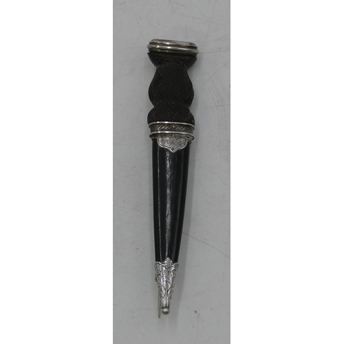 587 - A Scottish ebonised kilt pin in the form of a dirk, mounted with pink stone. 9.5cm long