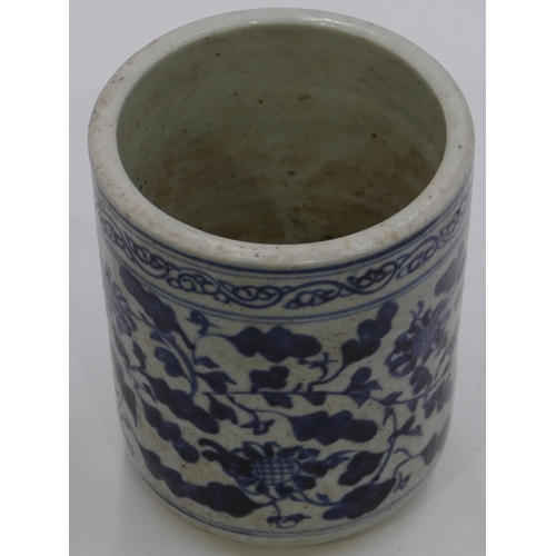59 - An Oriental cylindrical blue and white brush pot with allover floral and leaf decoration, 12.5cm hig... 