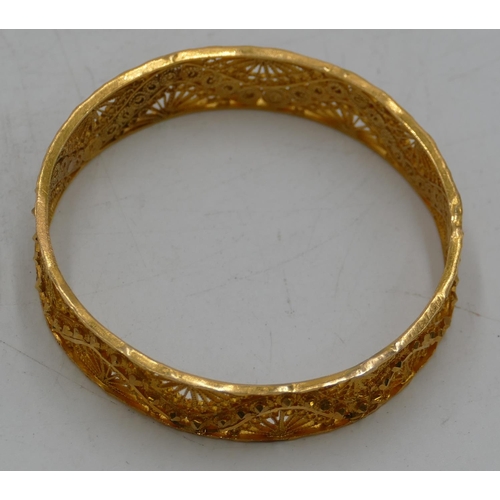 618 - A high carat gold Continental bangle with all over raised and pierced decoration, inner measurement ... 