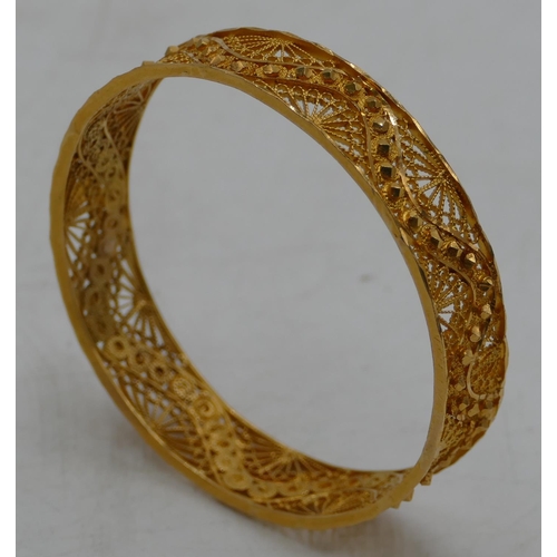 618 - A high carat gold Continental bangle with all over raised and pierced decoration, inner measurement ... 