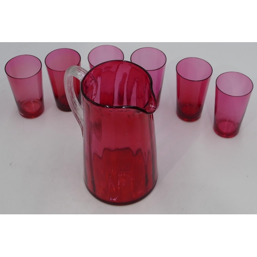 64 - A Cranberry glass round jug with clear reeded handle, 18cm high and 6 Cranberry beakers. (7)