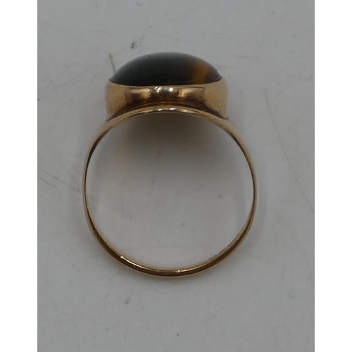 673 - A 9ct gold oval Tigers Eye ring, size P/Q, 5 grams gross.